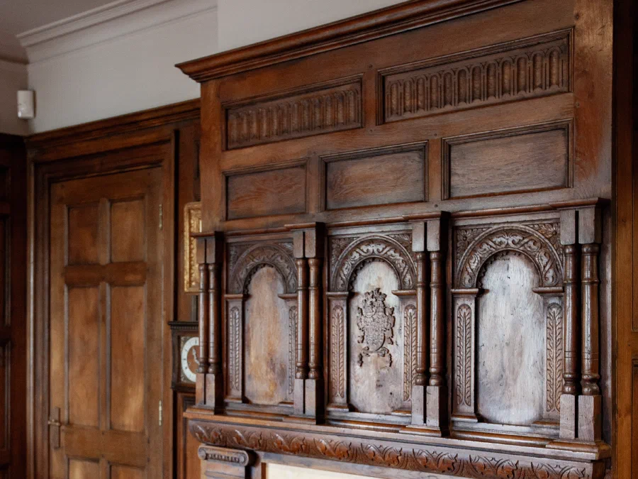 Carved timber overmantel beside an integrated panelled door