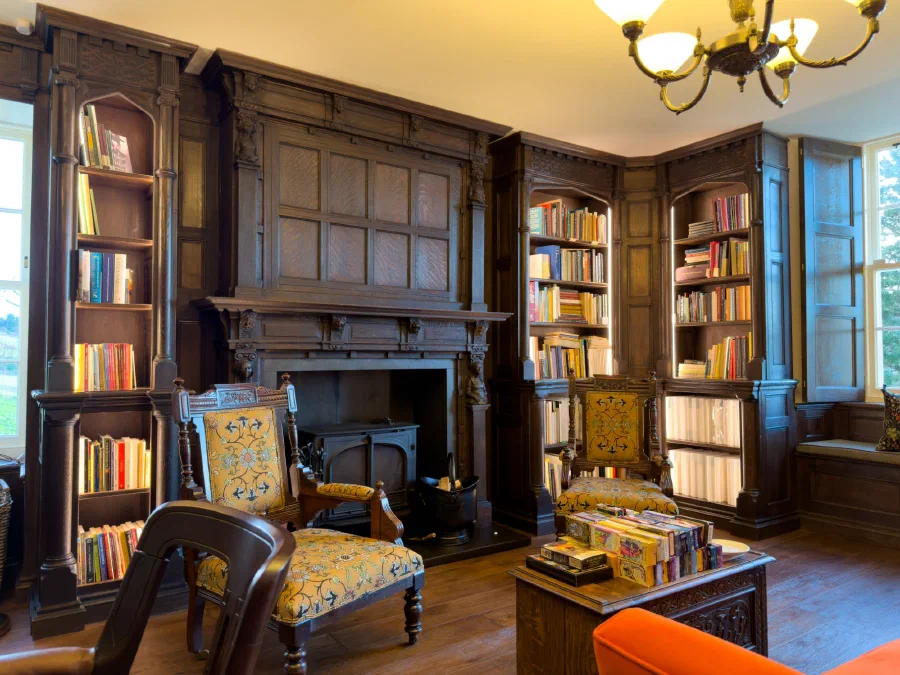 Dark oak library at Boleskine House with a panelled overmantel, carved figures and Gothic-arched bookcases