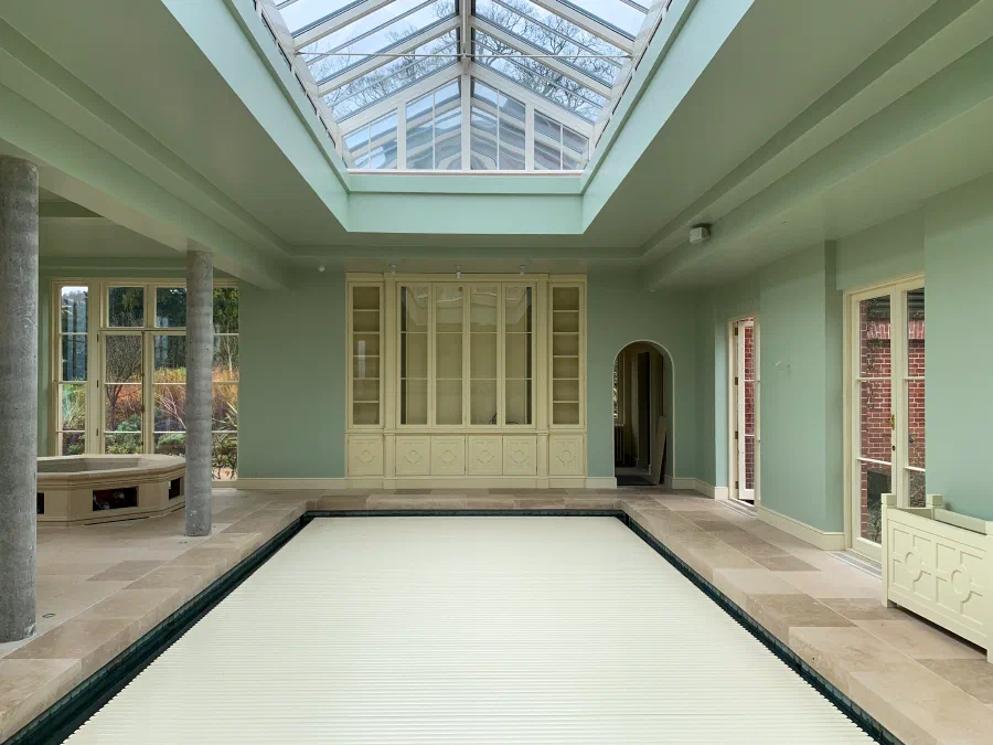 Pool hall beneath a glazed roof lantern with a painted fitted cabinet on the end wall