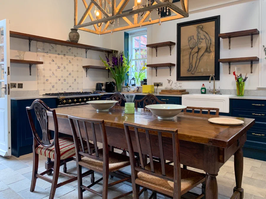 Kitchen with painted fitted cabinets, an open pantry cabinet and timber wall shelves