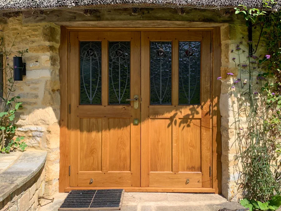 Pair of half-glazed oak entrance doors set within a traditional stone opening