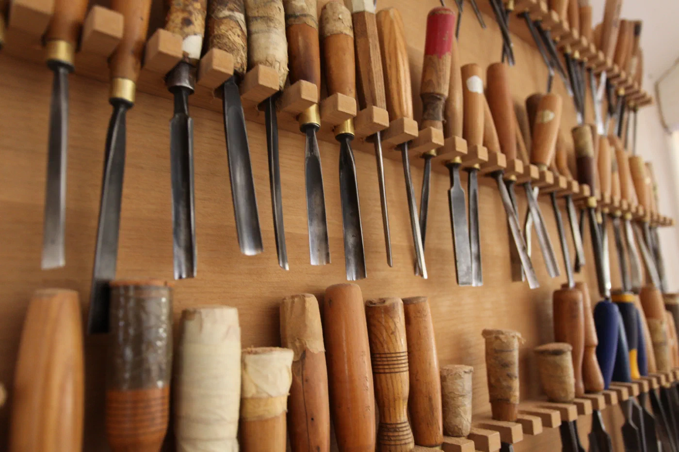 A wall of well-used carving chisels and gouges in the workshop