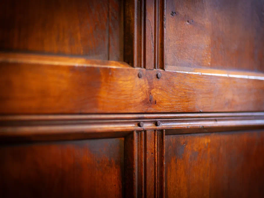 Close view of scratch-moulded oak panelling where the rails and muntins meet, each joint secured with two wooden pegs