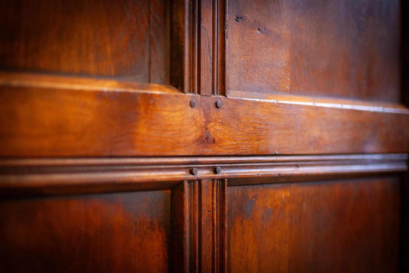 Close view of scratch-moulded oak panelling where the rails and muntins meet, each joint secured with two wooden pegs