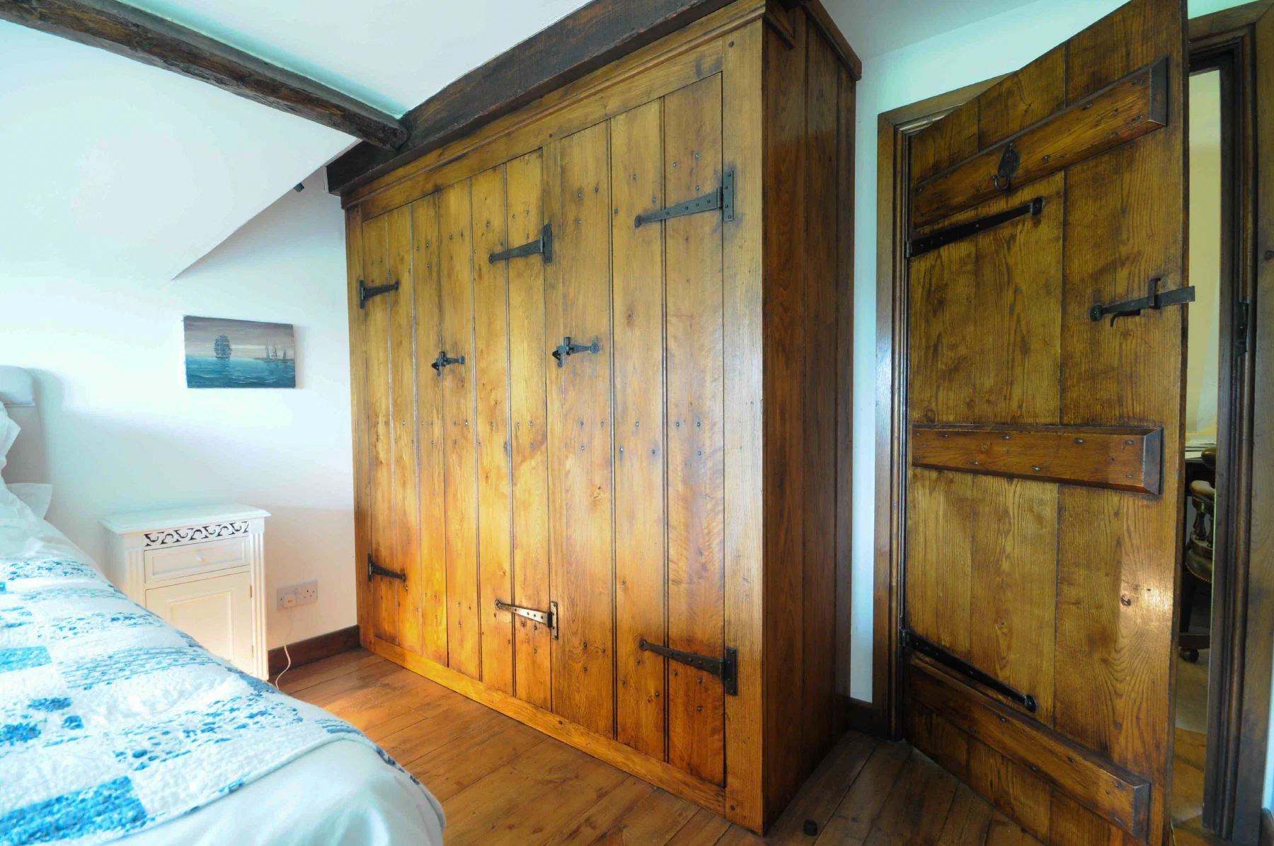 Plank doors to eaves storage beside a bed