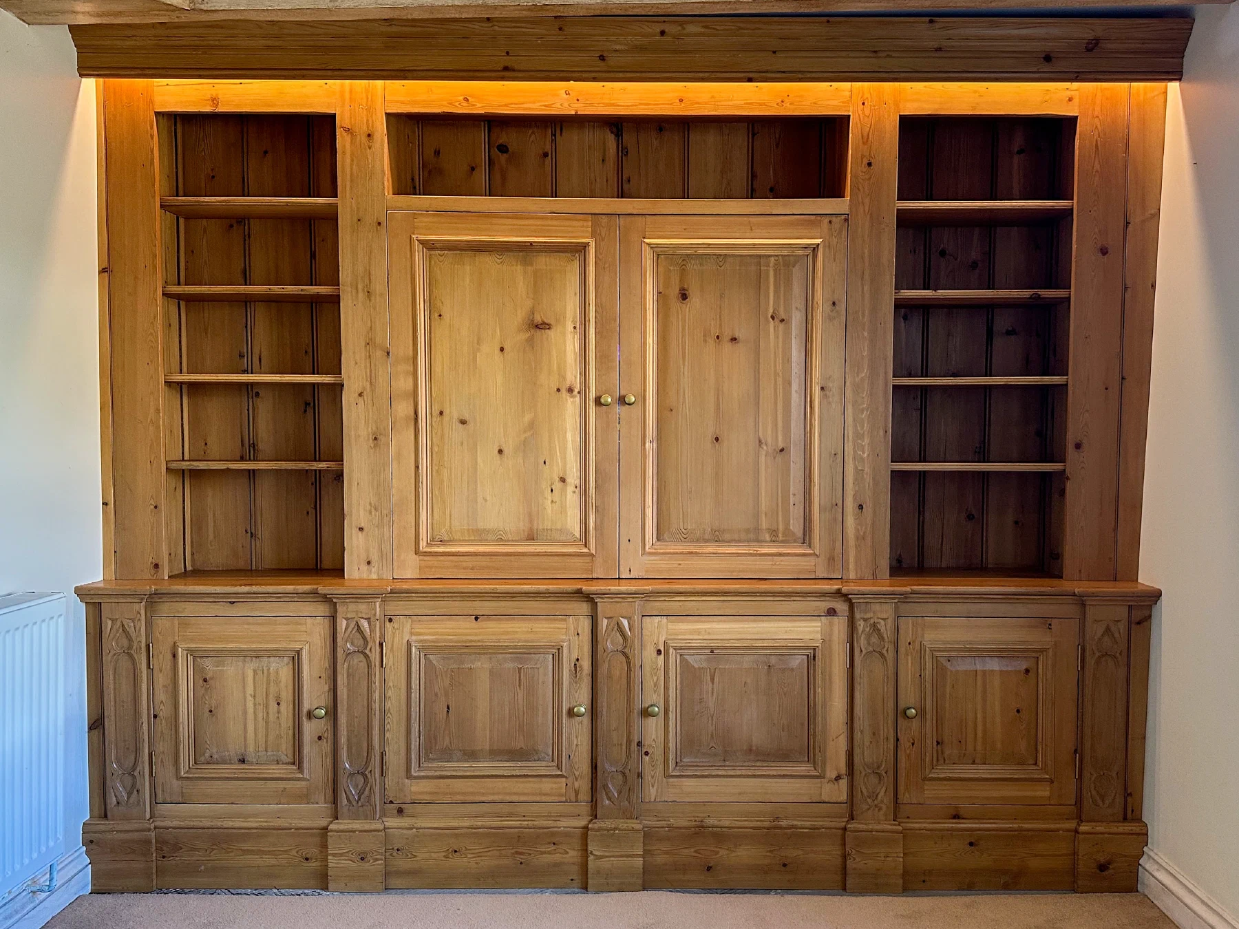 Closed fitted timber media cabinet with open side shelves and panelled lower cupboards