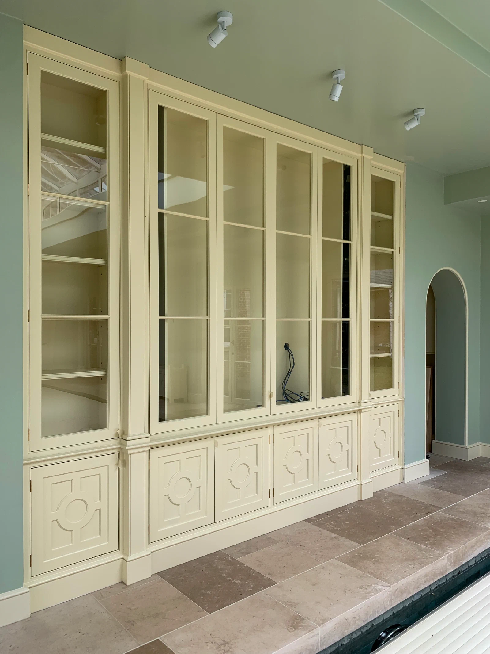 Painted cabinet in an indoor swimming pool room, with bi-fold doors that fold back into the cupboard