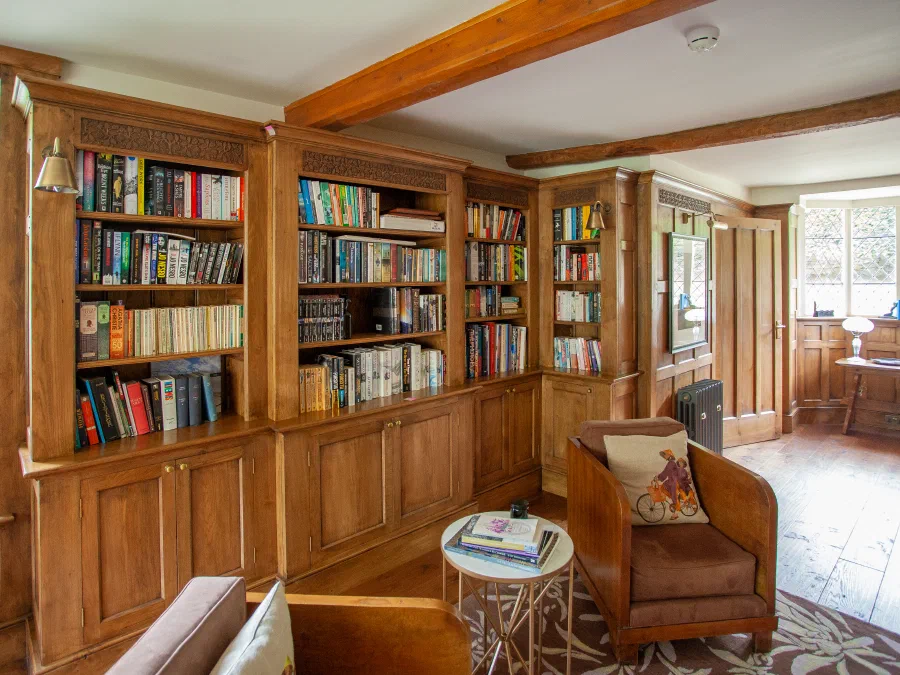 Fitted oak bookcases and reading chairs beneath an exposed beam