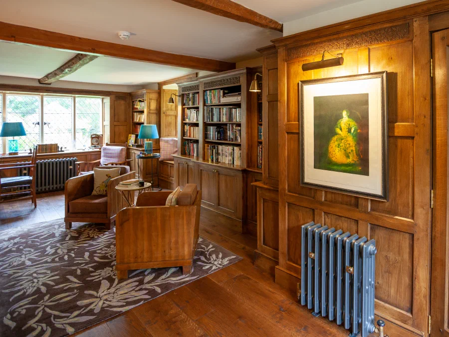 Oak panelling around a framed painting beside an armchair