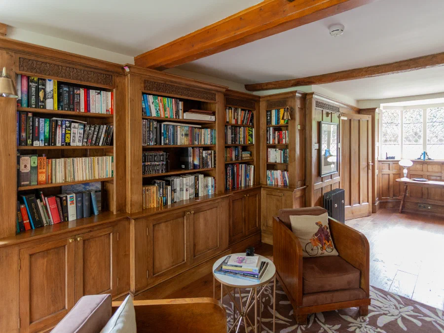 Reading chair within a corner of oak bookcases