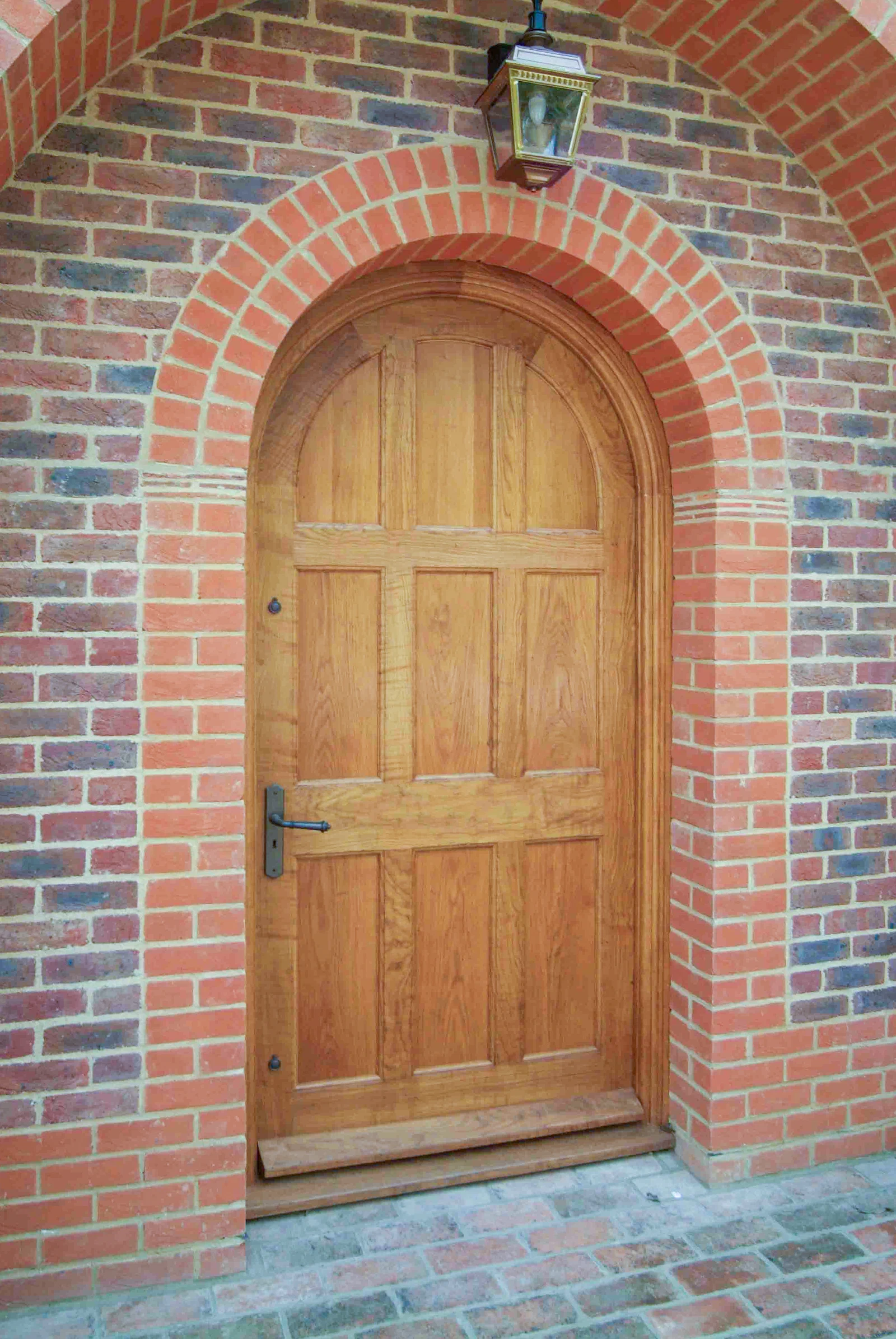 Arched oak entrance door set within a brick opening