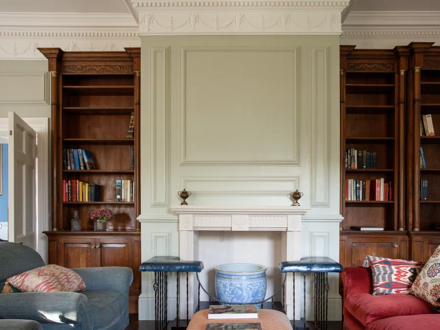 Painted panelling and carved bookcases around a fireplace