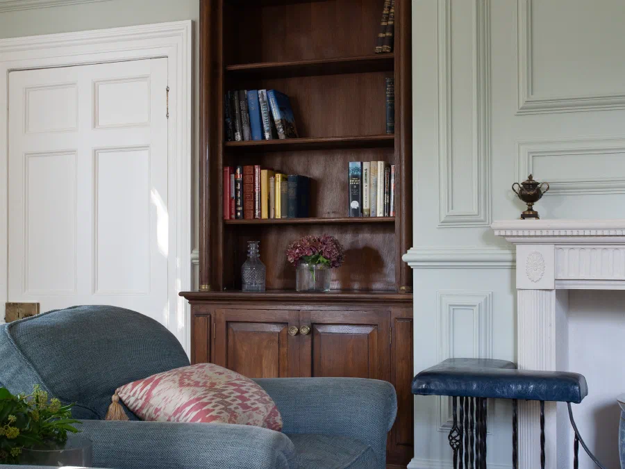 Painted panelling and a fitted oak bookcase beside the chimneypiece