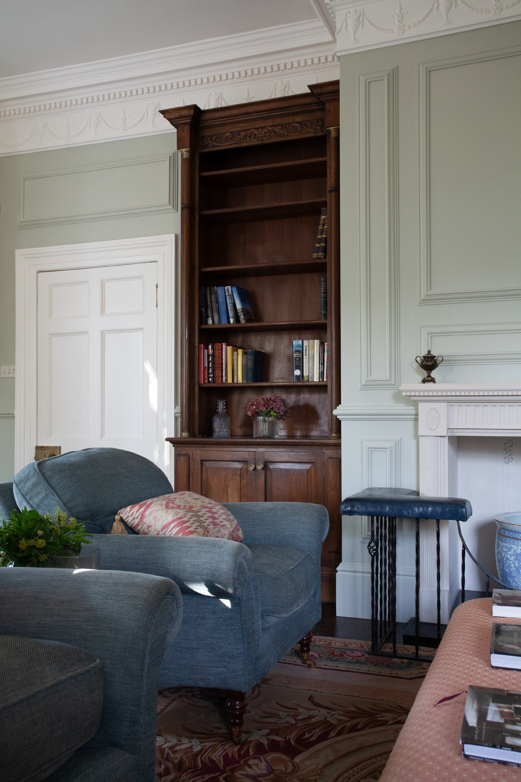Painted panelling and a fitted oak bookcase beside the chimneypiece at Alderwick House