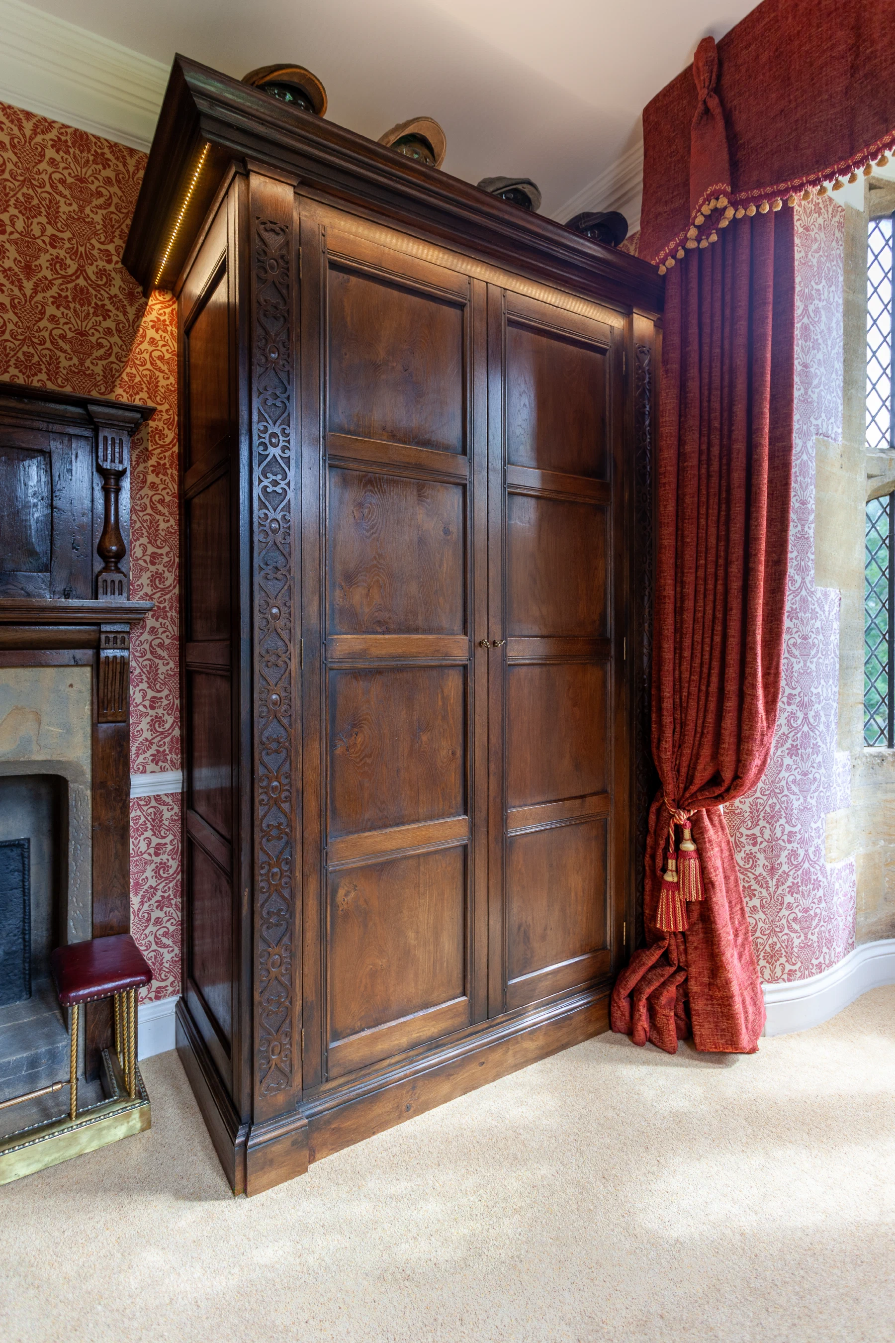 Window-side wardrobe with carved pilaster detail and red drapery
