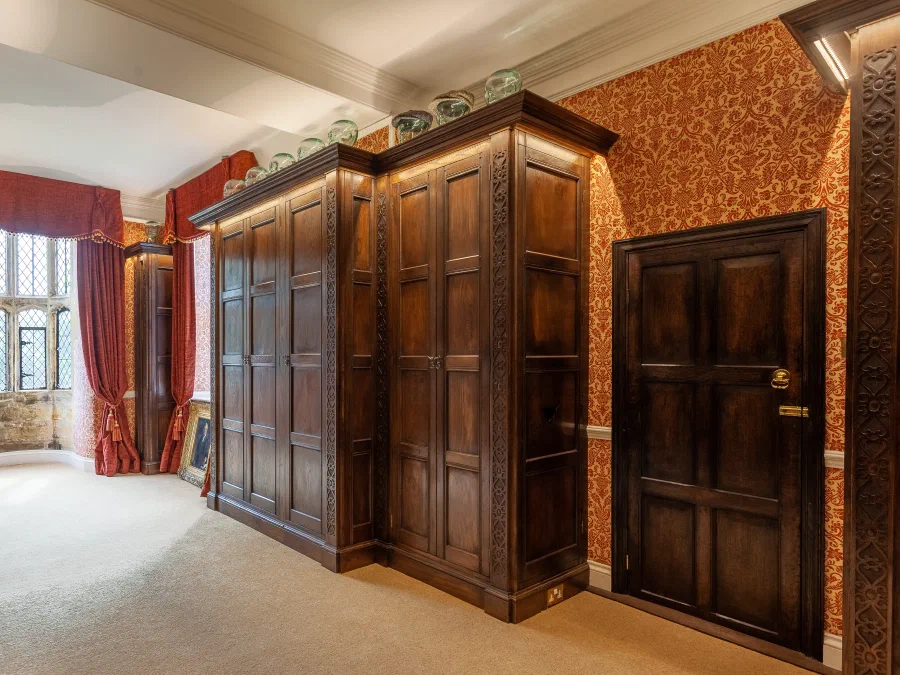 Wardrobes either side of a window with red curtains