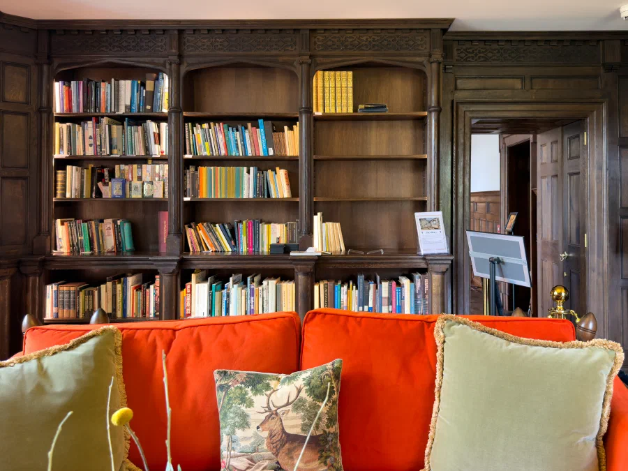 Long wall of fitted oak bookcases above panelled cupboards