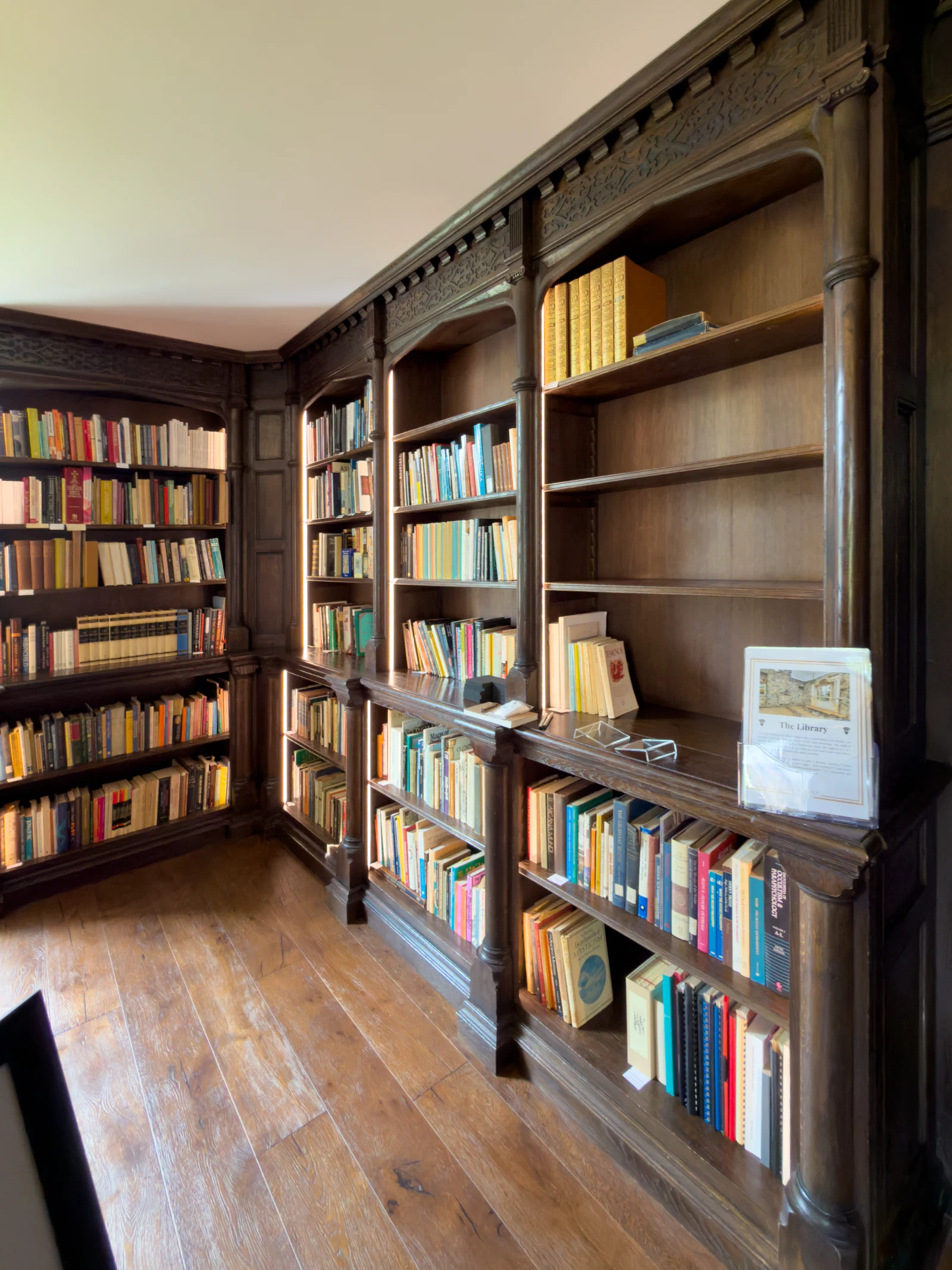 Dark oak bookcases with panelled cupboards turning the corner of the library