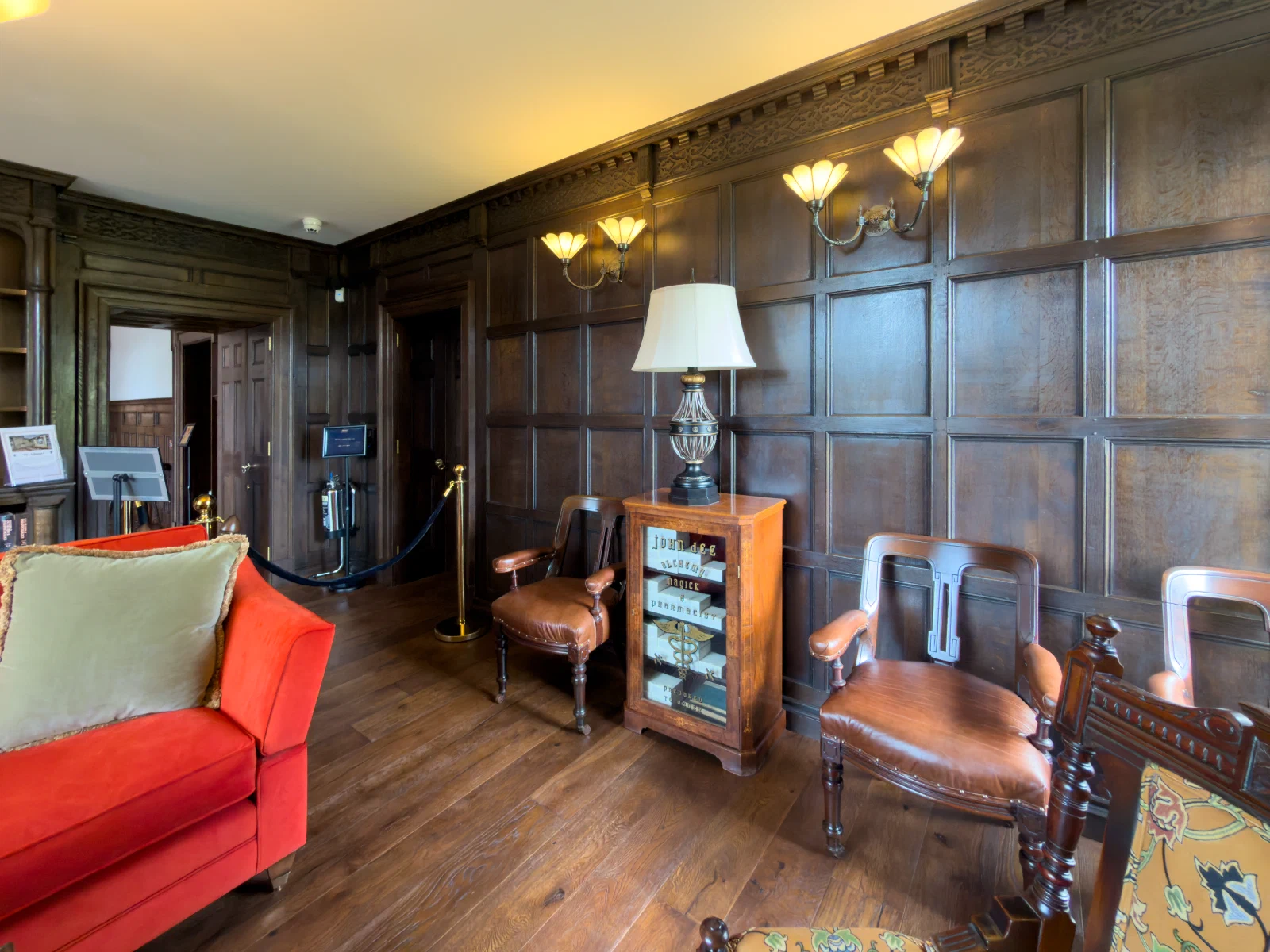 Panelled library wall with reading chairs and a lamp