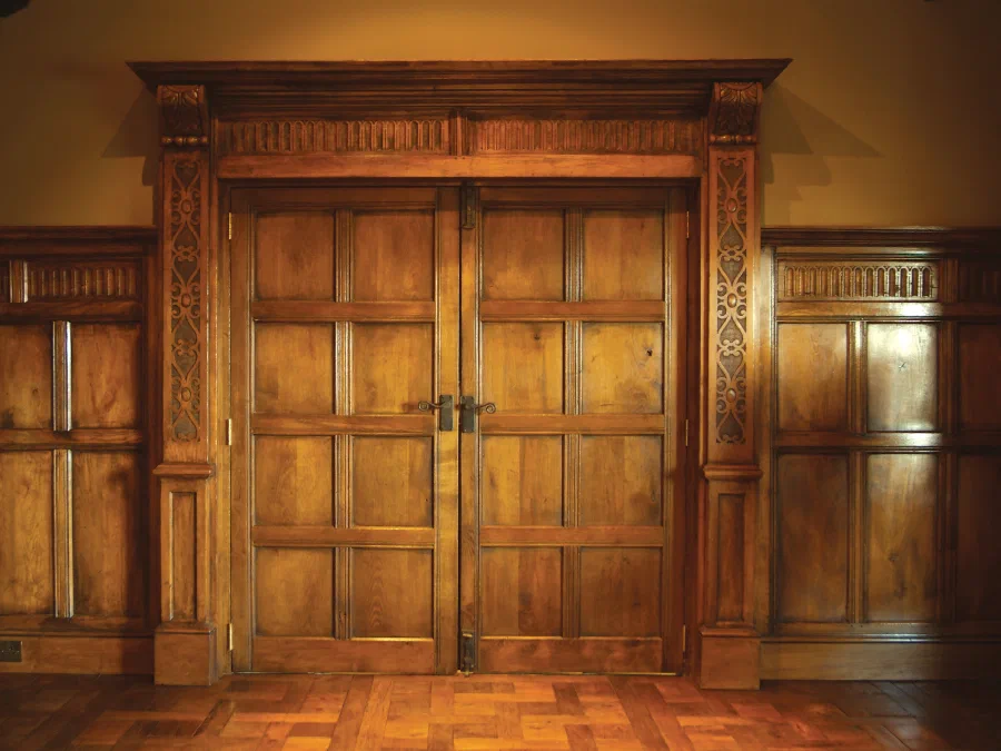 Panelled oak double doors with a carved surround in the Great Hall