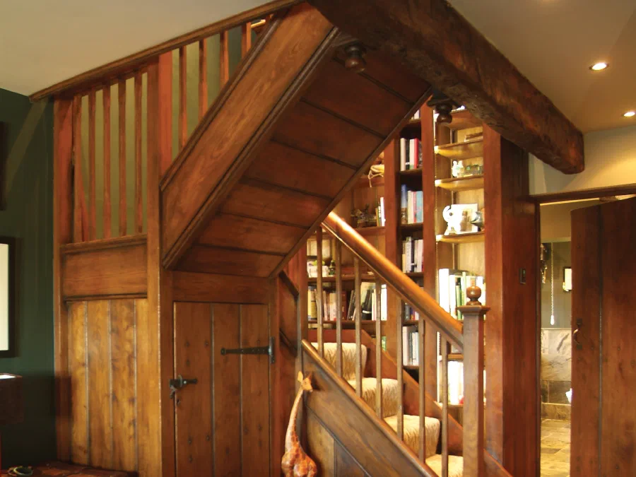Oak staircase beside lit fitted bookcases