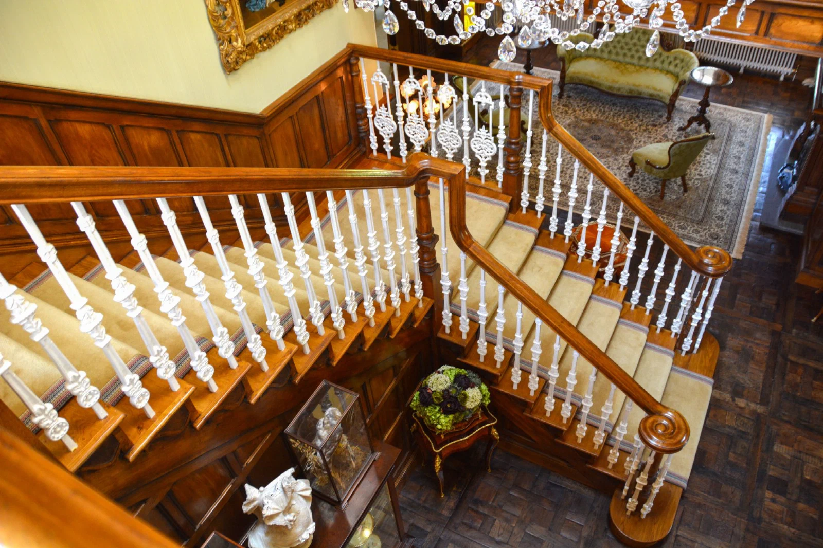 Open-string oak staircase with cast-iron balusters and scrolled handrails, seen from the landing