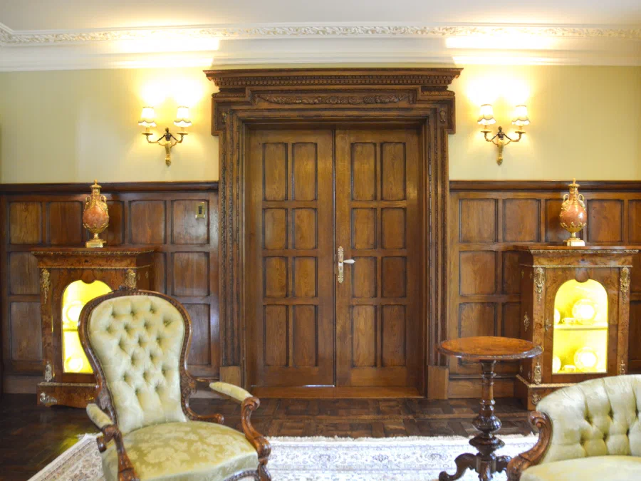 Panelled oak double doors between wall lights above dado panelling
