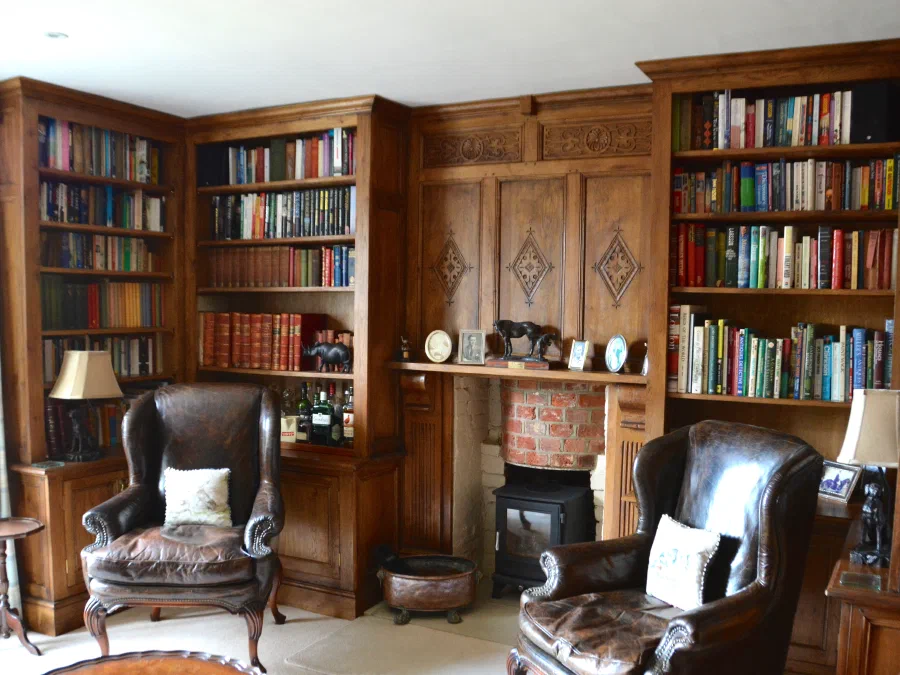 Oak study at Reed Farmhouse with fitted bookcases either side of a carved fireplace wall