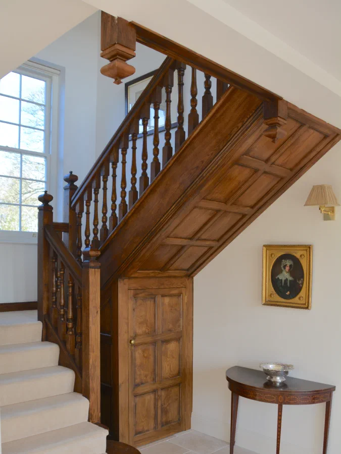 New oak staircase with a carpeted flight and a panelled cupboard beneath