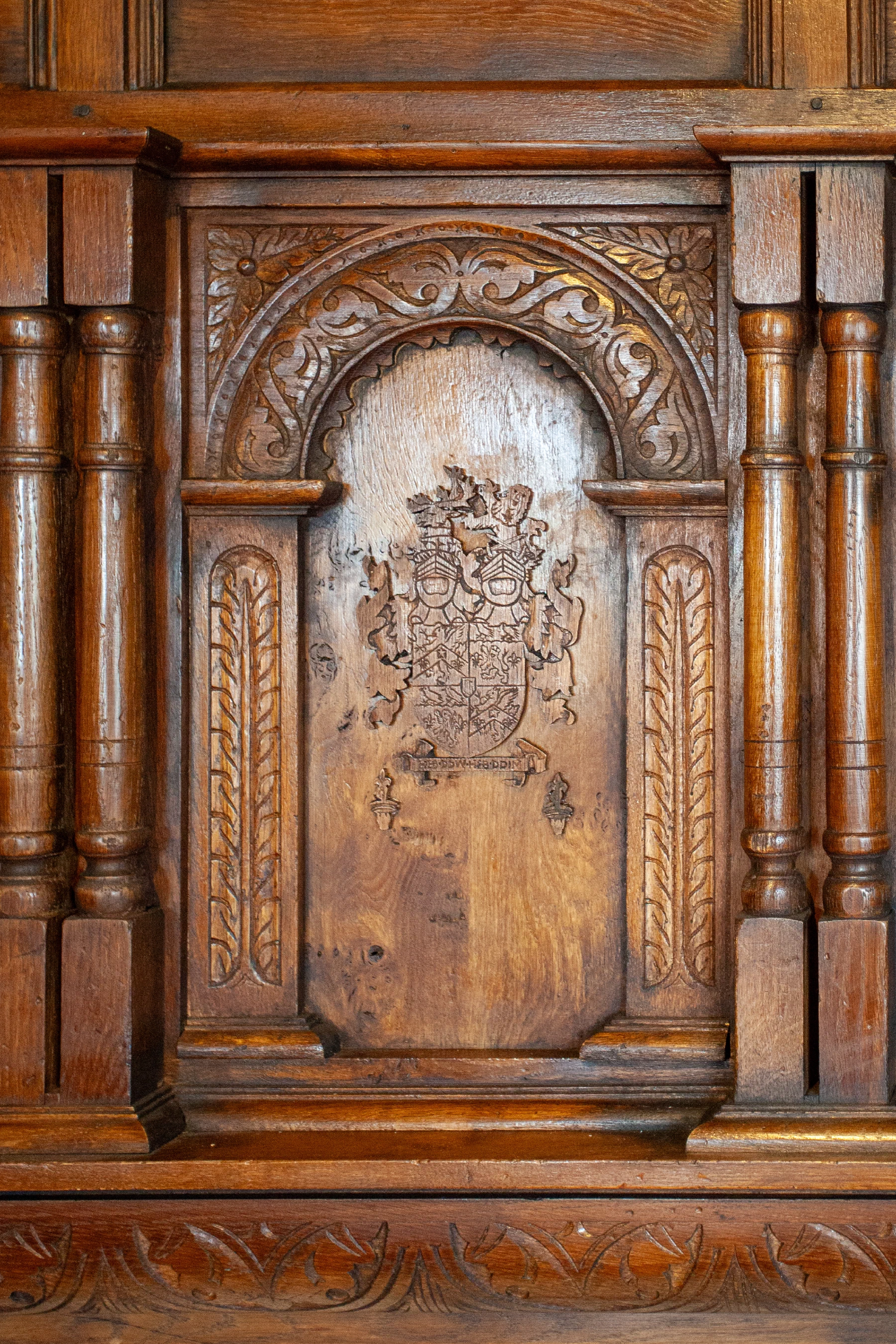 Carved oak panel with an arched armorial design