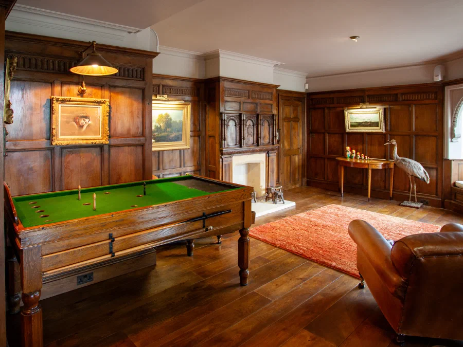 Oak-panelled games room with pictures hung within the panel layout