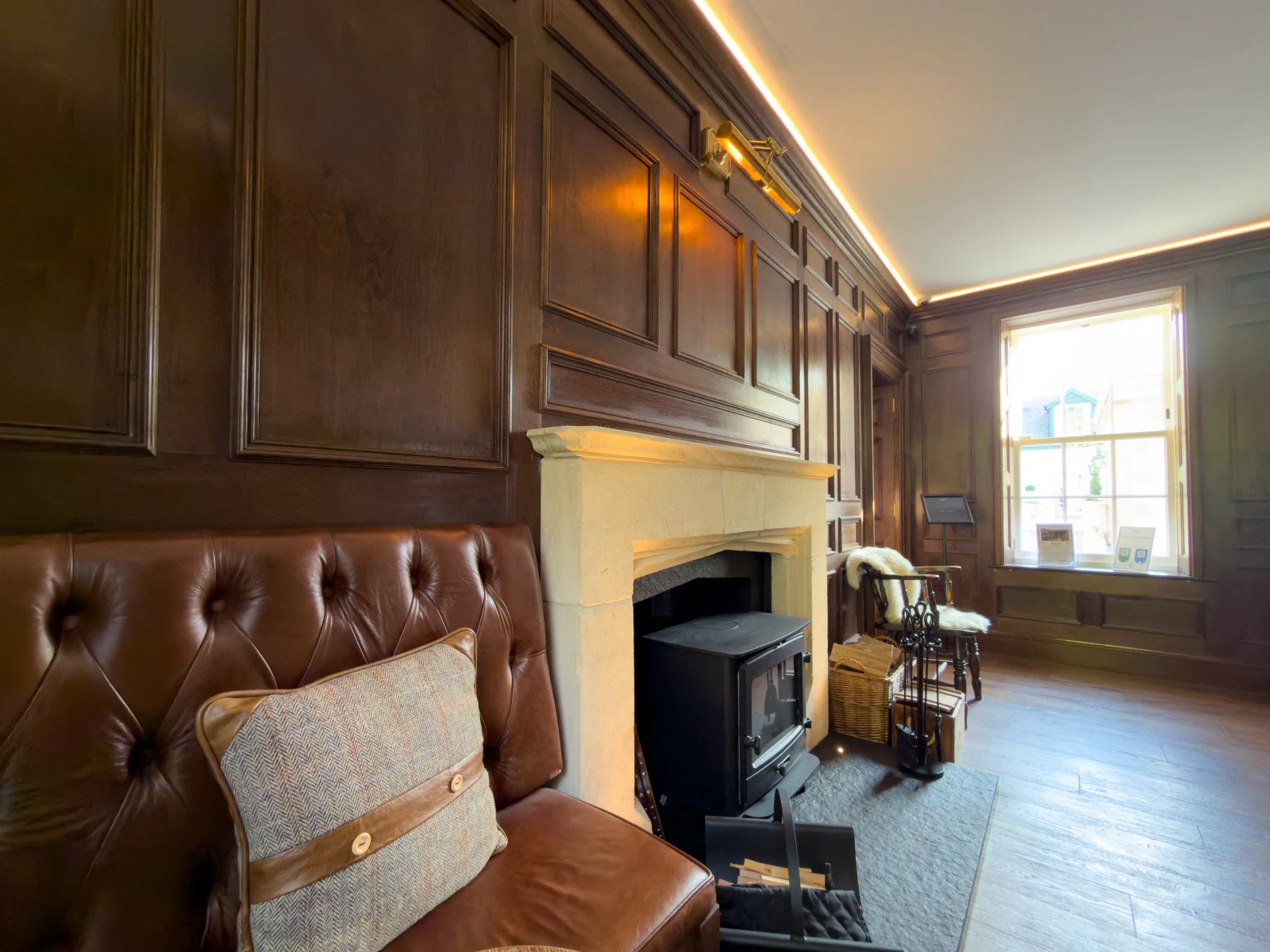 Fitted leather seating and oak panelling beside the fireplace