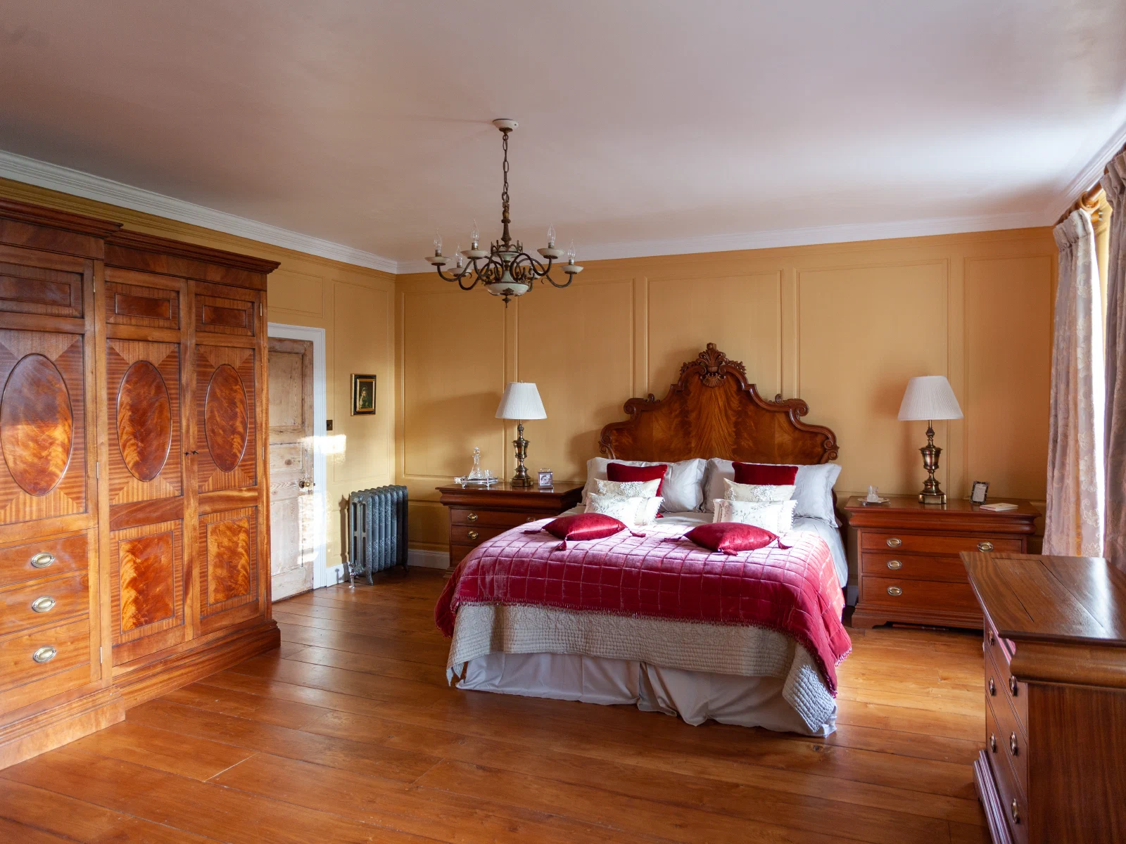 Flame mahogany bed and bedside cabinets against restored pine panelling