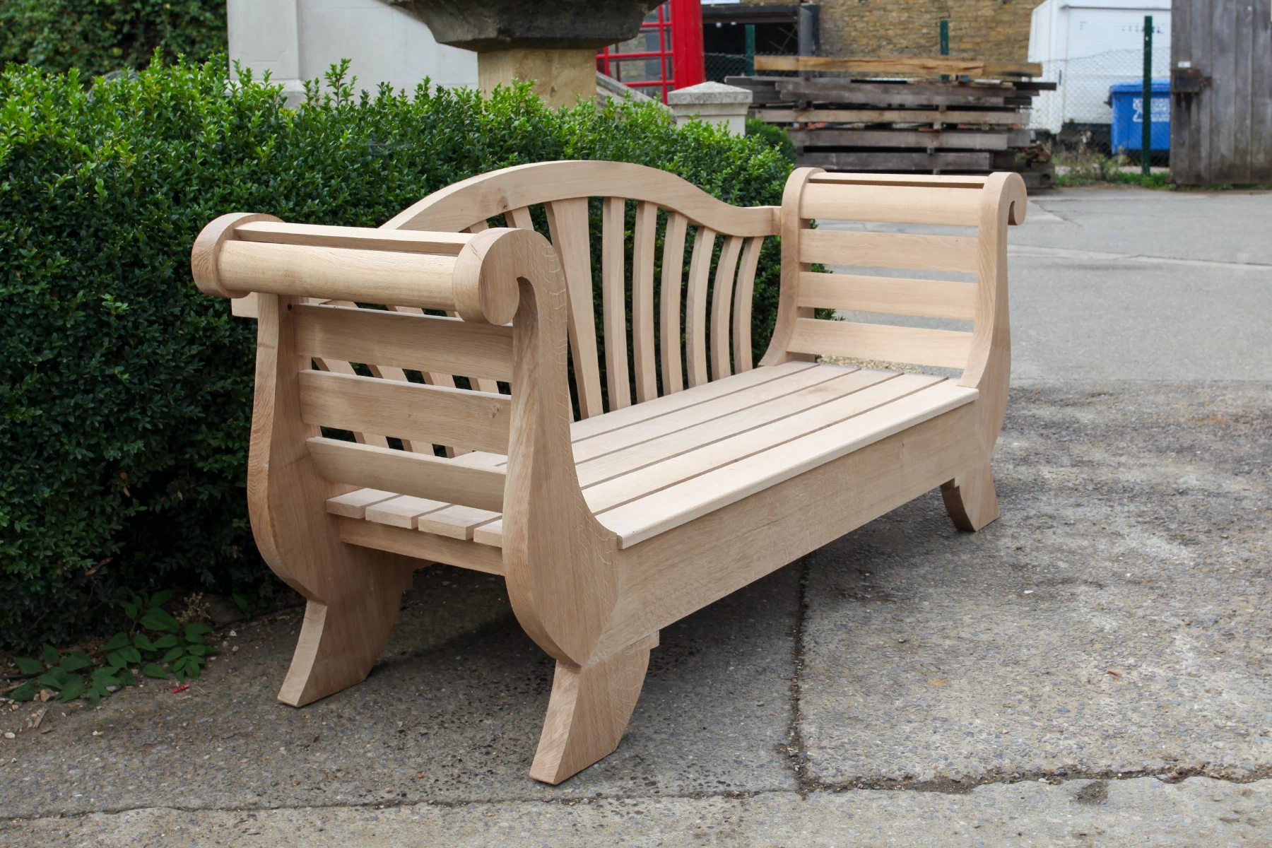 Carved timber garden bench with a rolled back and shaped arms