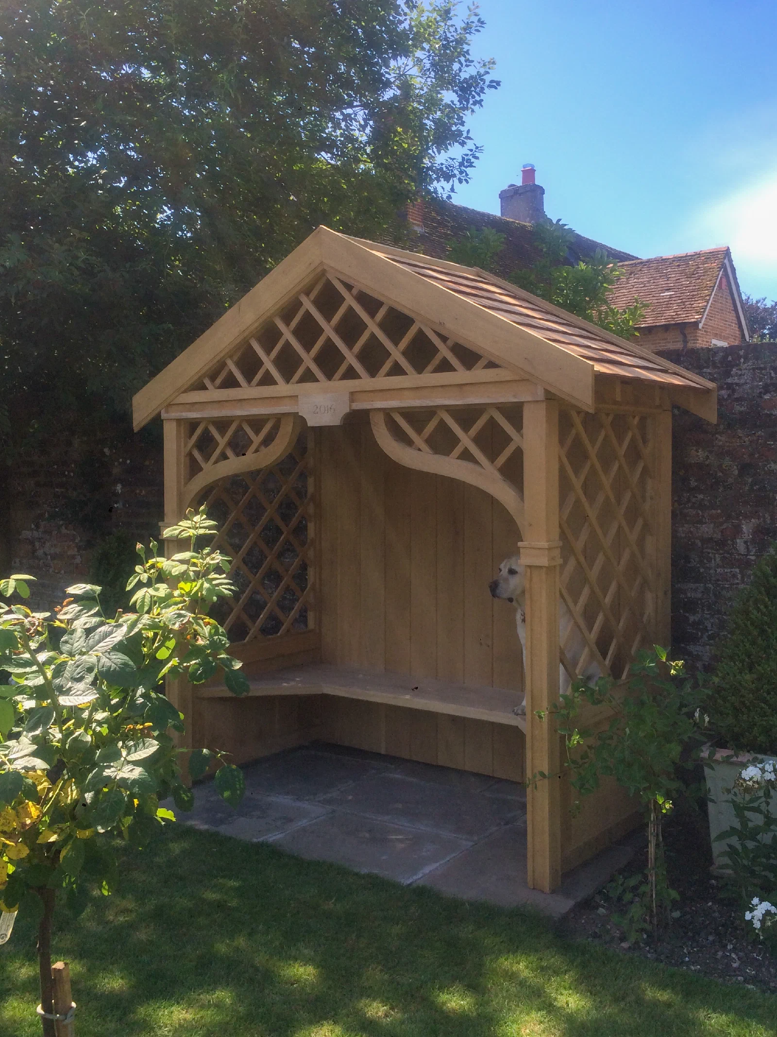 Timber garden shelter with a pitched roof and built-in seat