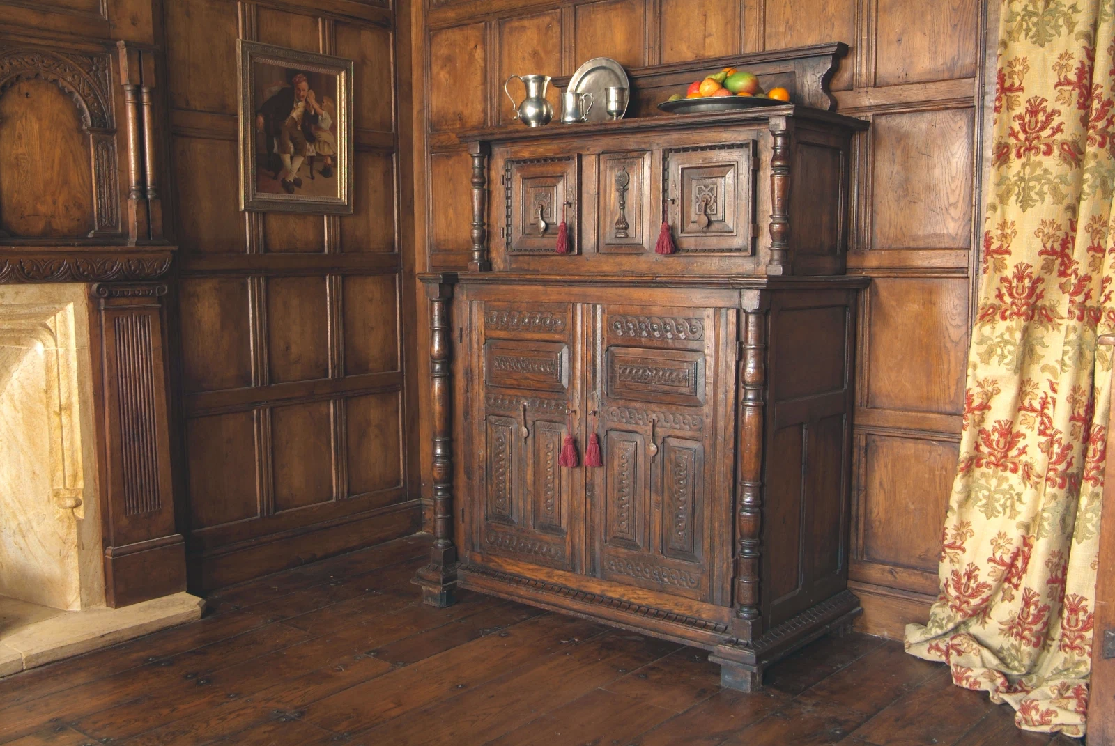 Carved oak court cupboard within a panelled room