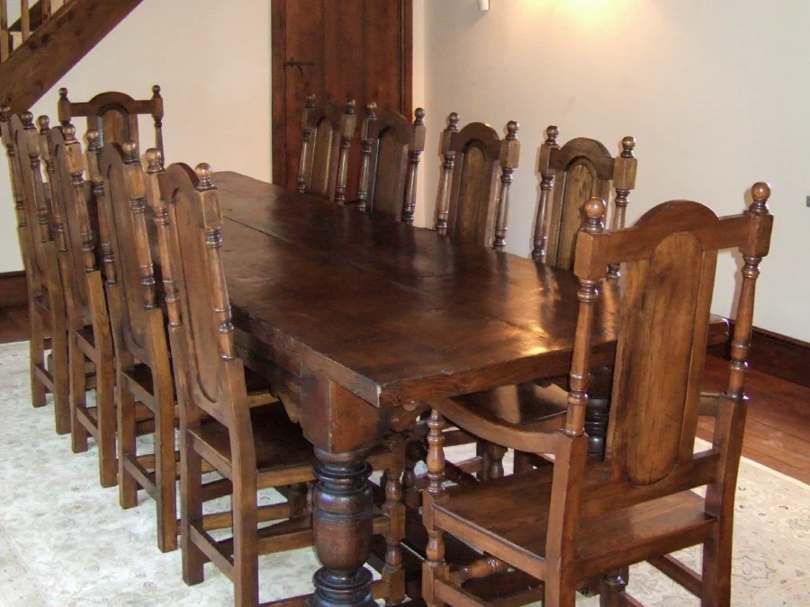 Long oak dining table with a set of chairs beneath a beamed ceiling