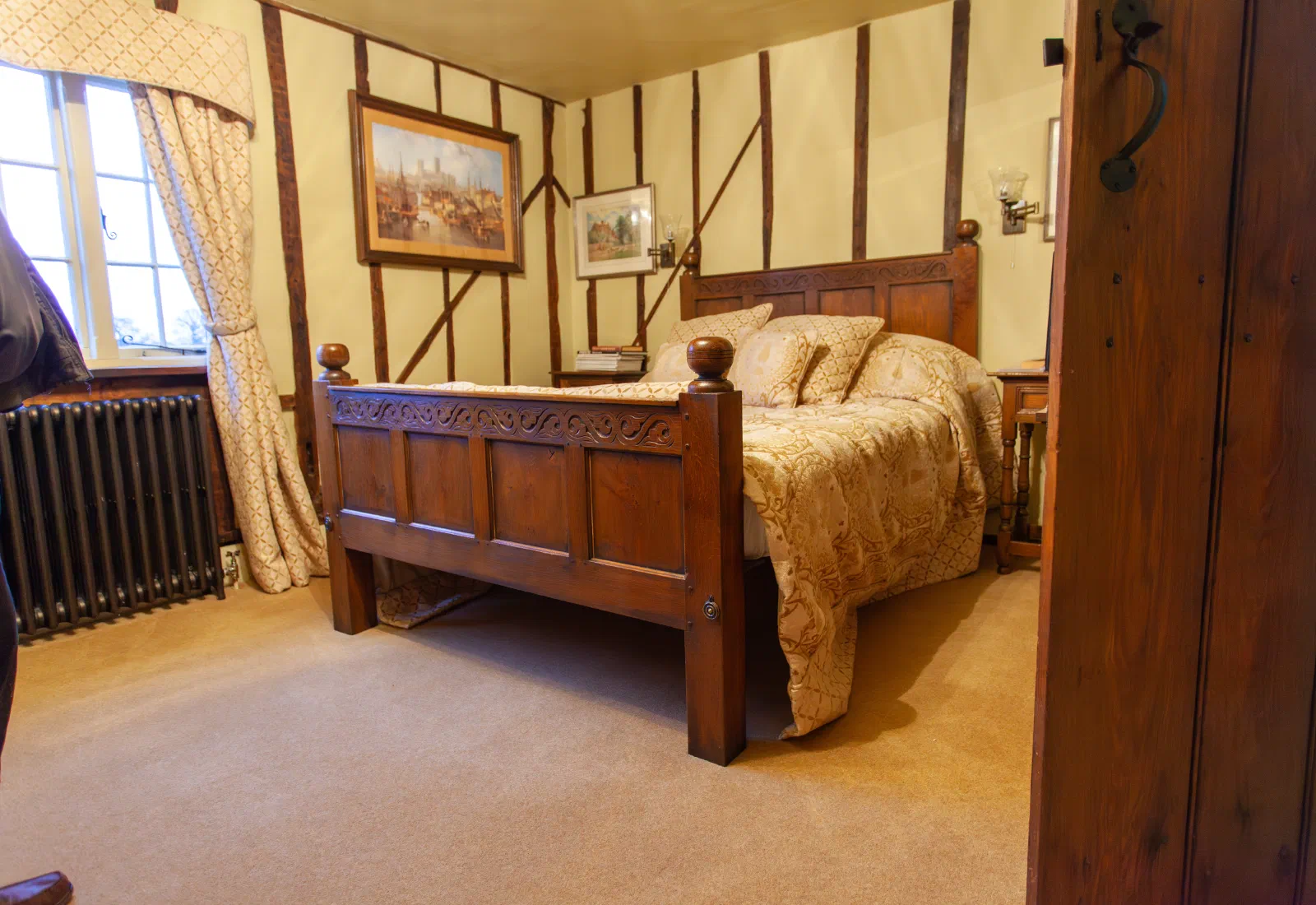 Carved timber bed in a bedroom with exposed historic framing
