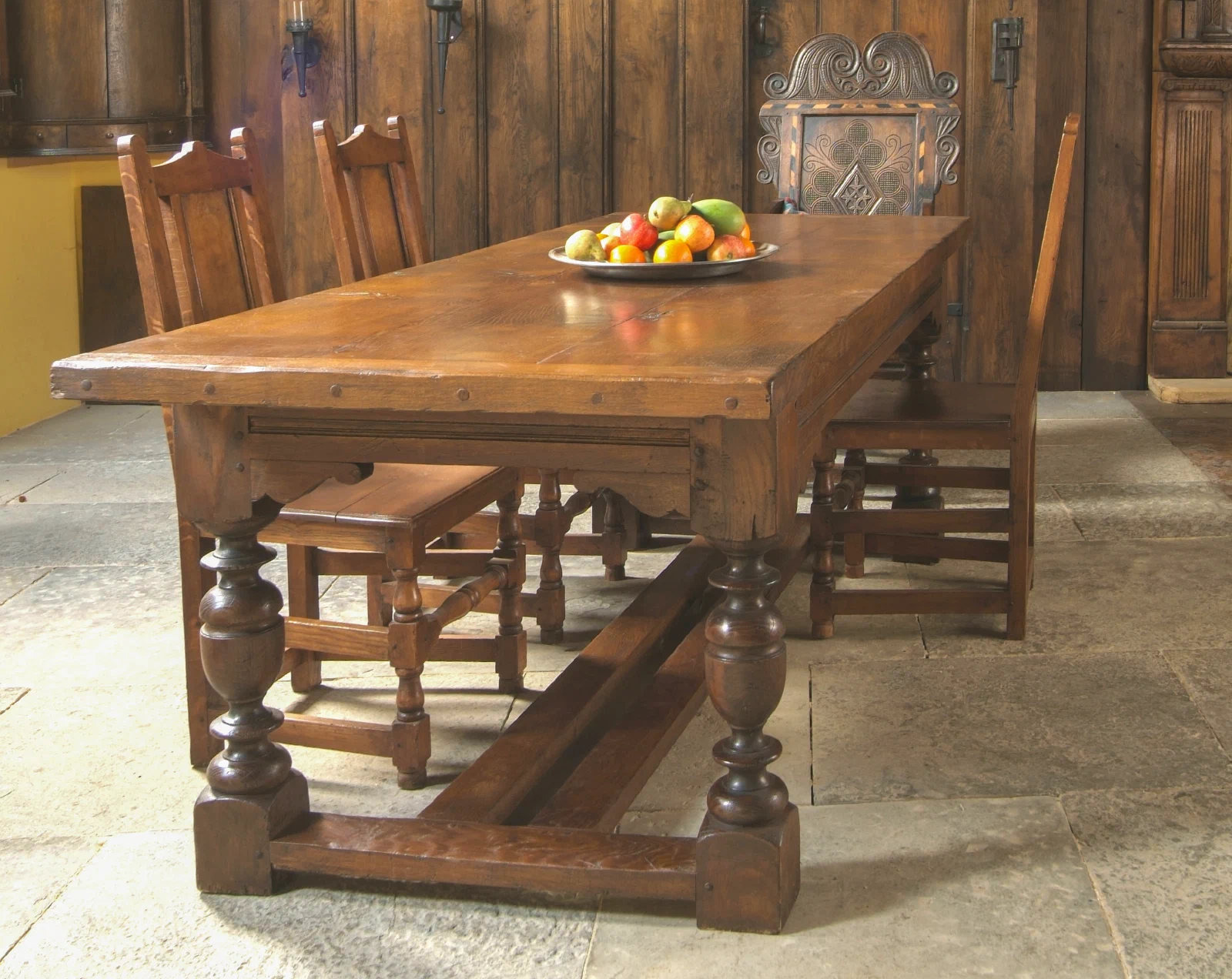 Oak refectory table with a simple channel moulding, set with chairs in a panelled room