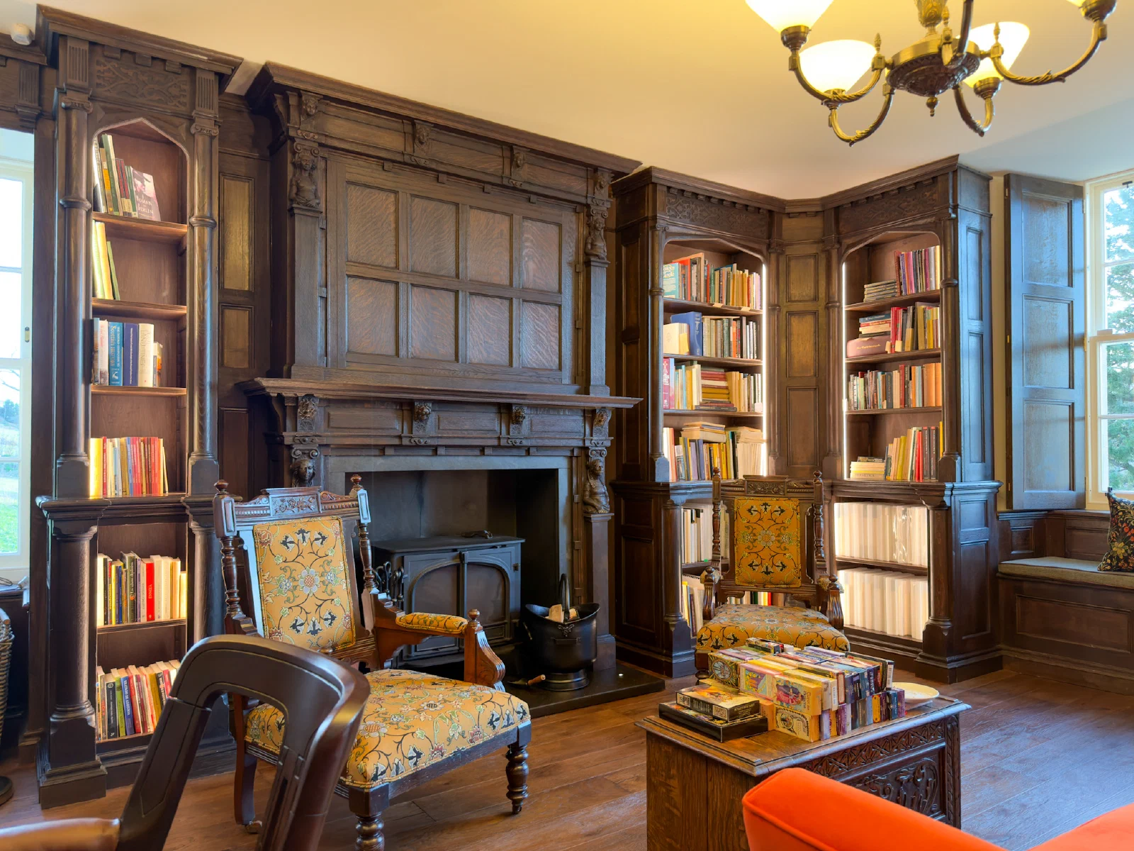 Completed oak library with panelled walls, fitted bookcases and a carved overmantel
