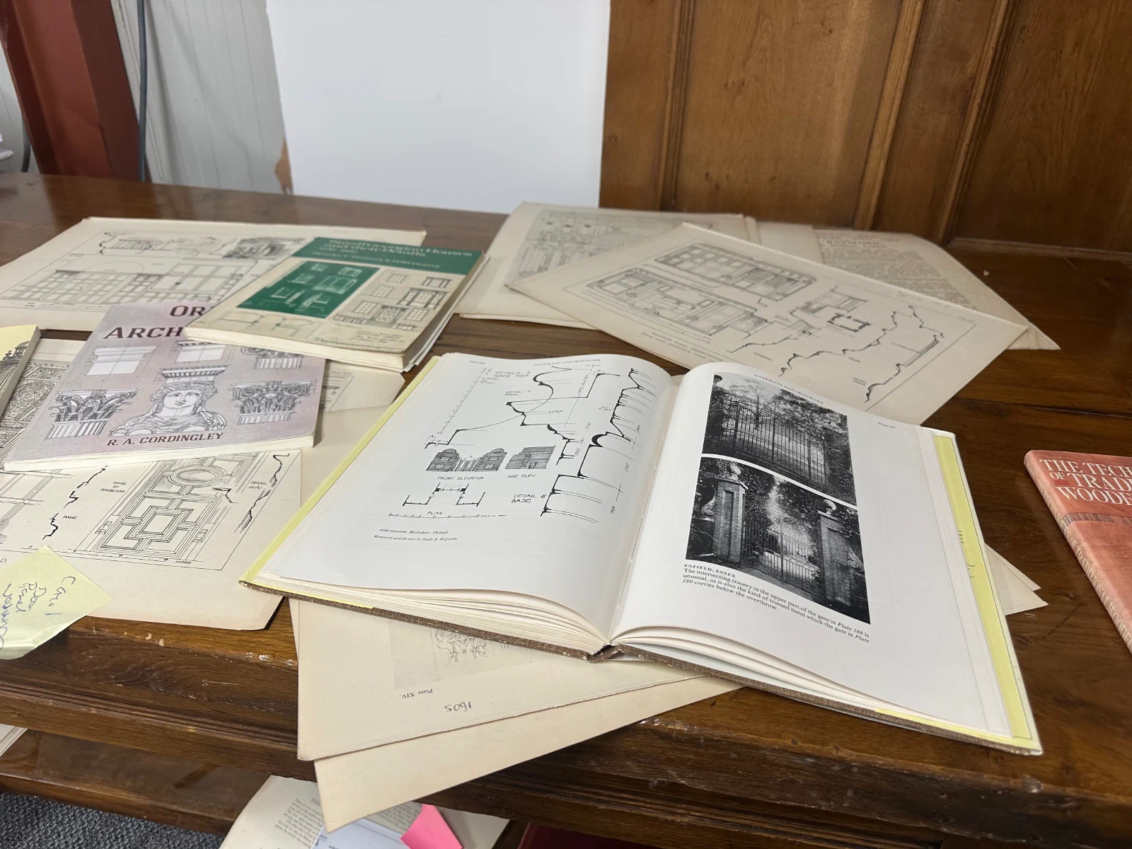Architectural reference books and measured joinery drawings on a table