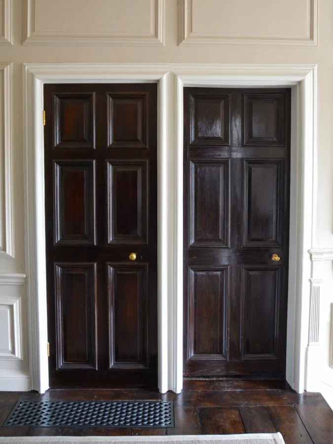 Two dark six-panelled doors set within painted bolection panelling