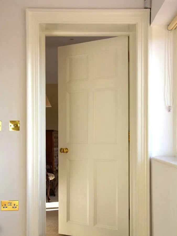 Painted six-panelled door standing open within a matching architrave
