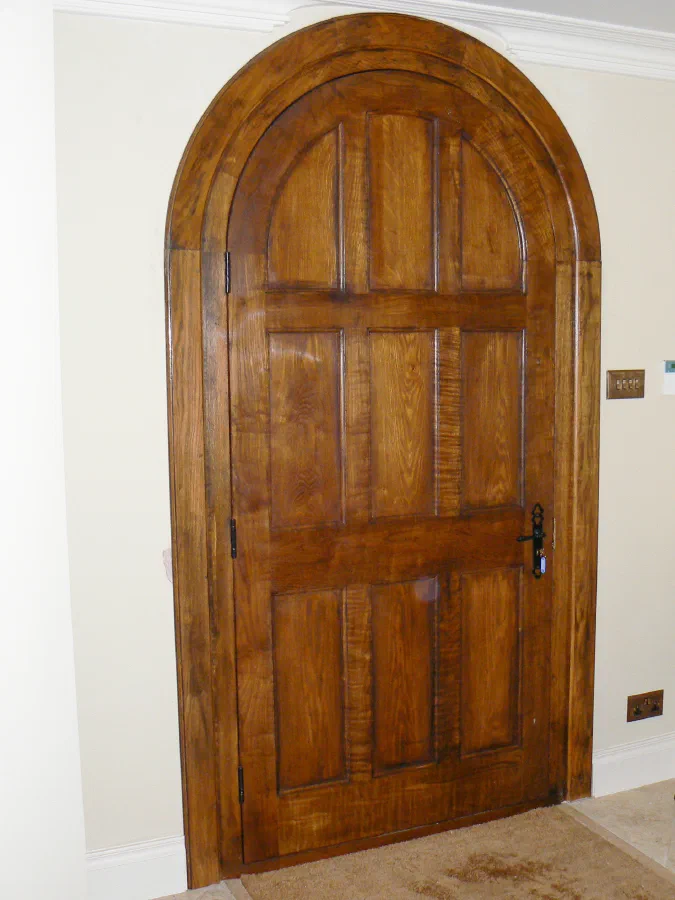 Round-headed panelled timber door with a matching curved surround