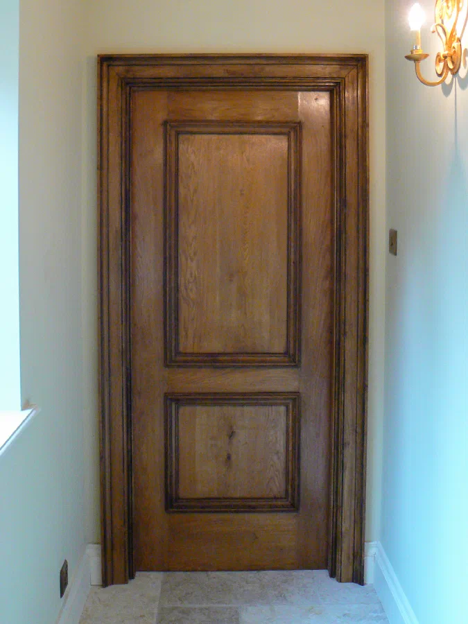 Two-panelled timber door with raised mouldings and a matching architrave