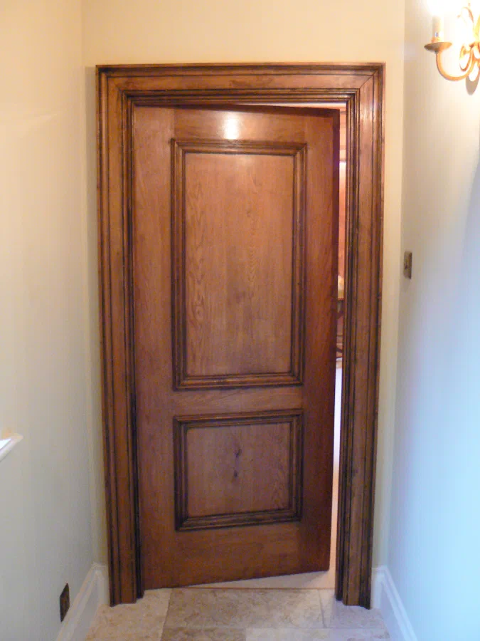 Two-panelled timber door standing partly open within its moulded frame