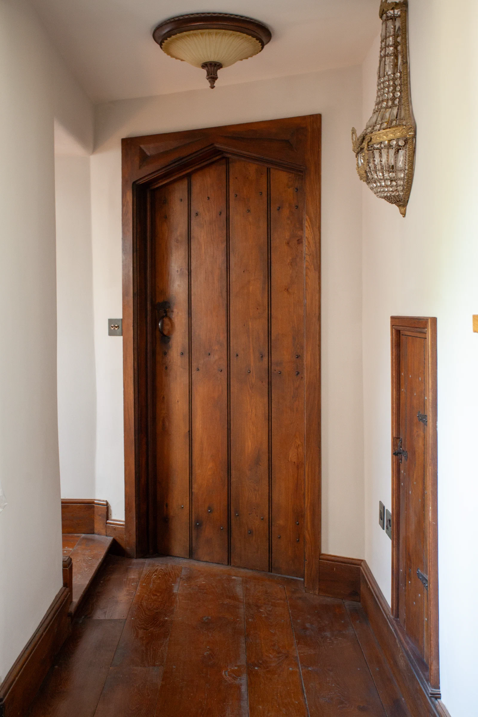 Tudor-arched internal oak plank door at a timber stair landing