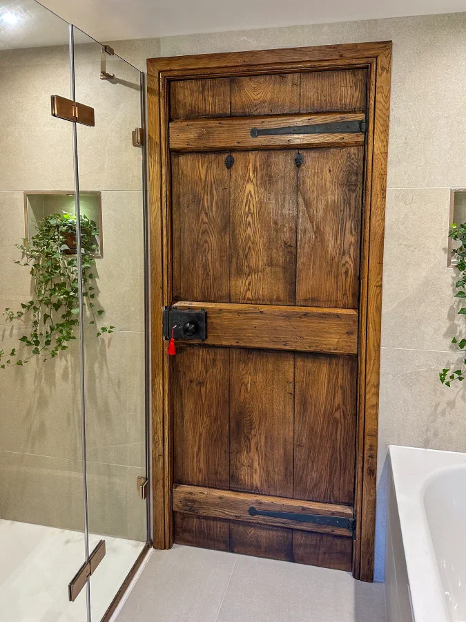 Ledged internal oak plank door with black ironmongery in a bathroom