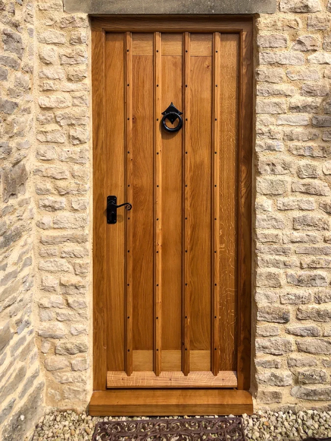 Oak door with applied ribs, studwork and a ring knocker in a stone opening