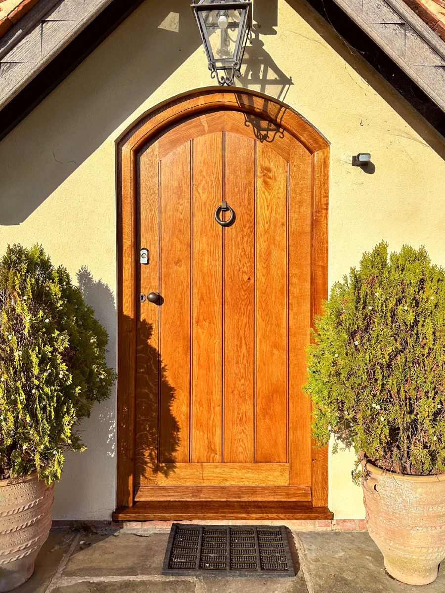 Arched oak framed plank door beneath a small entrance gable